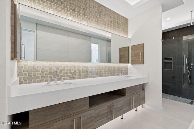 full bath featuring double vanity, tasteful backsplash, a tile shower, and a sink