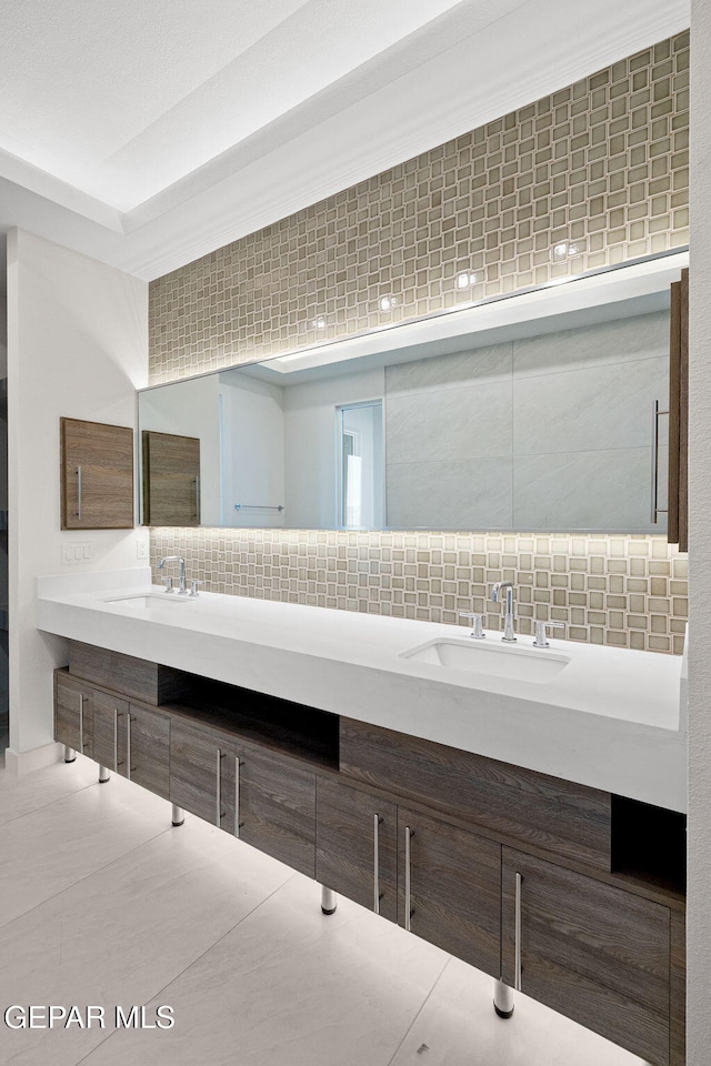 bathroom with double vanity, backsplash, and a sink