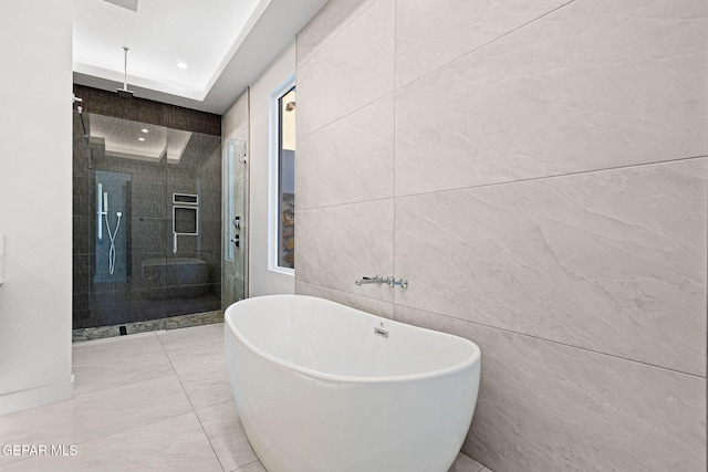 full bath featuring a freestanding bath, a shower stall, and tile walls