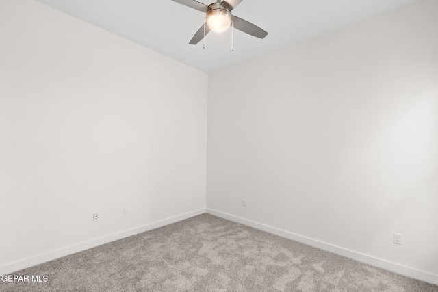 carpeted spare room featuring ceiling fan and baseboards