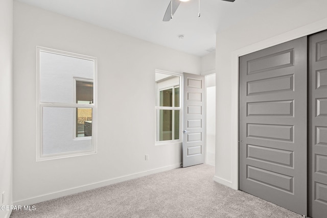 unfurnished bedroom with a ceiling fan, carpet flooring, baseboards, and multiple windows