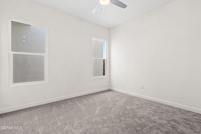 carpeted spare room featuring a ceiling fan and baseboards