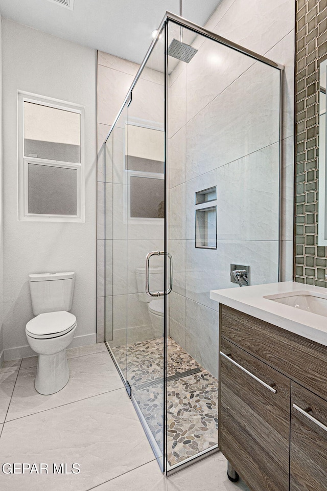 bathroom with baseboards, a shower stall, toilet, and vanity