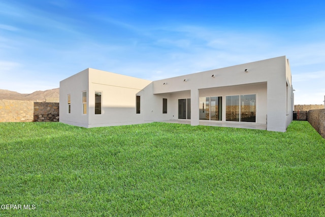 back of house with a lawn and stucco siding