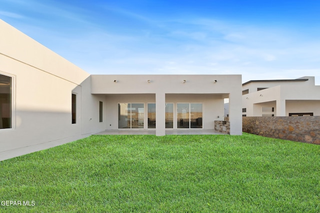 rear view of property featuring a yard and stucco siding