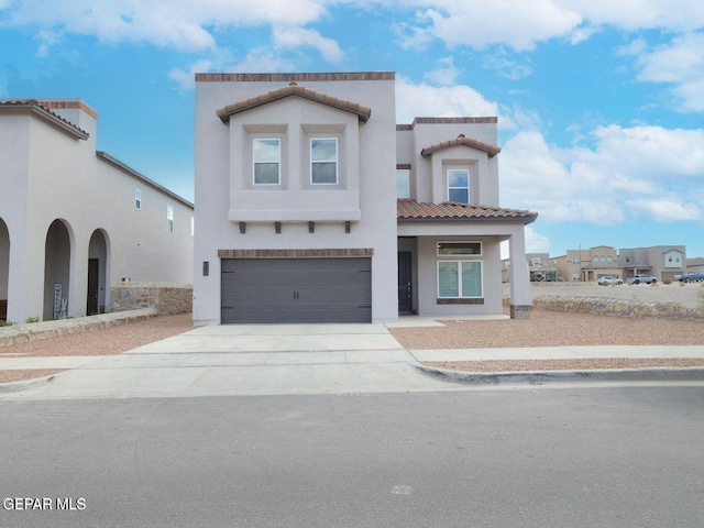 mediterranean / spanish-style house featuring a garage, concrete driveway, a tile roof, and stucco siding