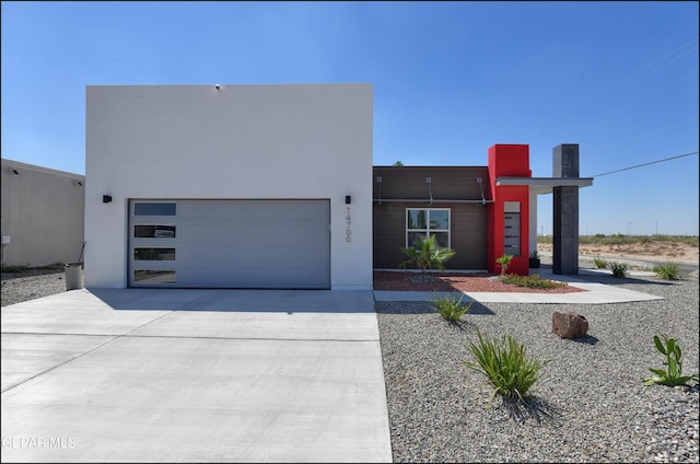 modern home featuring concrete driveway, an attached garage, and stucco siding