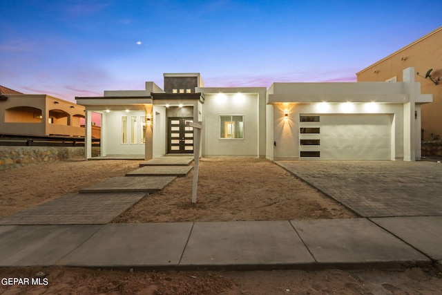 view of front of house featuring decorative driveway, an attached garage, and stucco siding