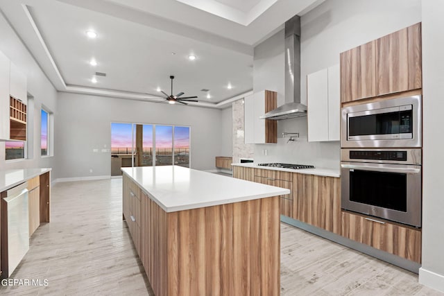 kitchen featuring wall chimney exhaust hood, modern cabinets, stainless steel appliances, and a center island