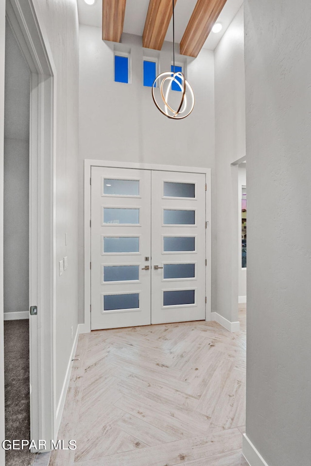 foyer entrance with a high ceiling, baseboards, beamed ceiling, and french doors