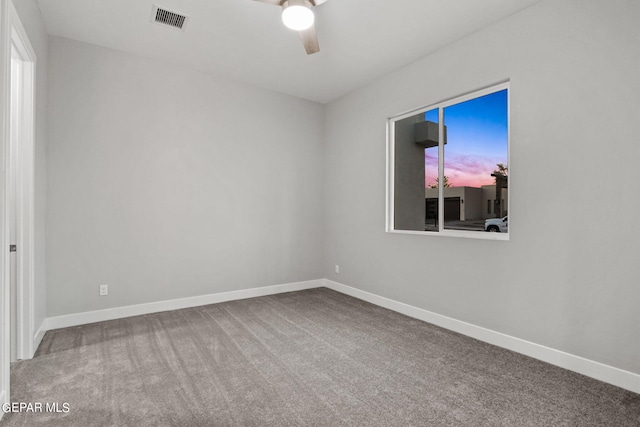 carpeted spare room with a ceiling fan, visible vents, and baseboards
