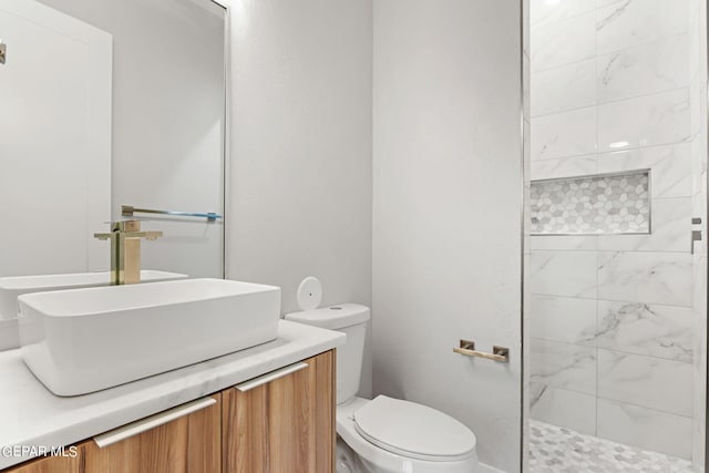 full bath with toilet, tiled shower, and vanity