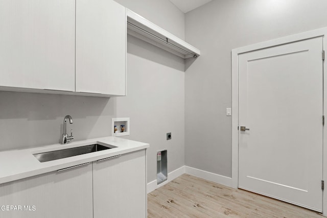 clothes washing area with cabinet space, hookup for a washing machine, hookup for an electric dryer, light wood-type flooring, and a sink