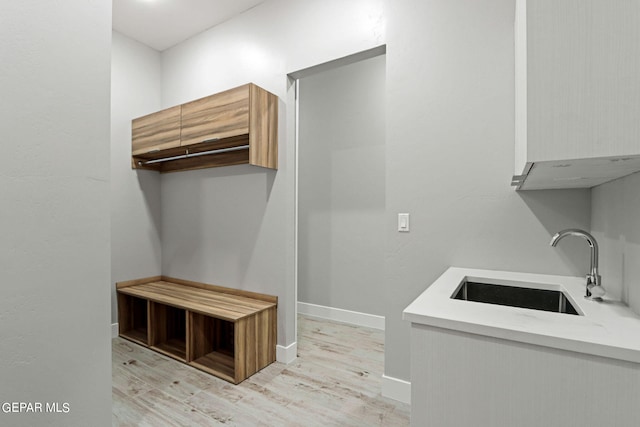 interior space with light wood-type flooring, a sink, and baseboards