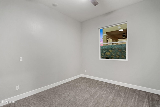 carpeted spare room featuring ceiling fan and baseboards