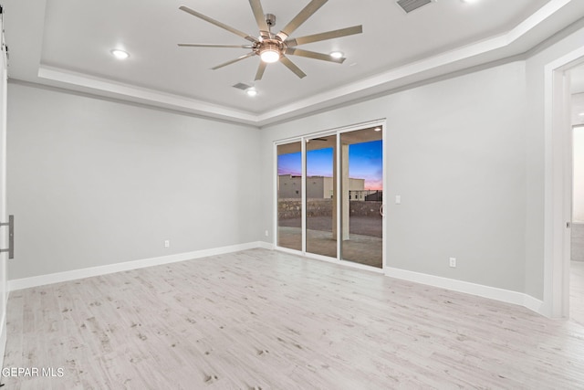 unfurnished room featuring light wood-type flooring, a raised ceiling, visible vents, and baseboards