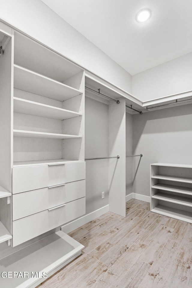 walk in closet with light wood-style floors