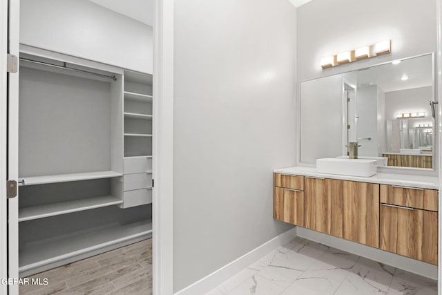 bathroom with marble finish floor, a spacious closet, baseboards, and vanity