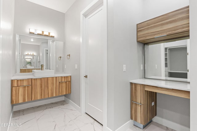 bathroom with marble finish floor, vanity, and baseboards