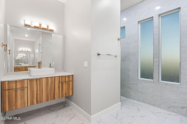 full bath featuring marble finish floor, baseboards, walk in shower, and vanity