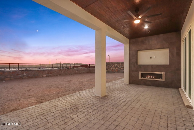 view of patio featuring a ceiling fan, a large fireplace, and a fenced backyard