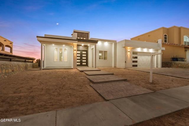 view of front facade with an attached garage, driveway, and stucco siding
