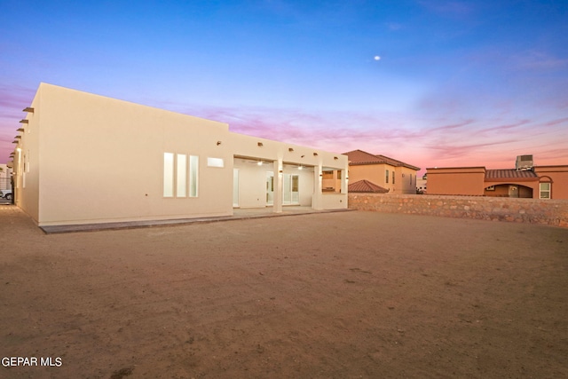 back of house at dusk with stucco siding