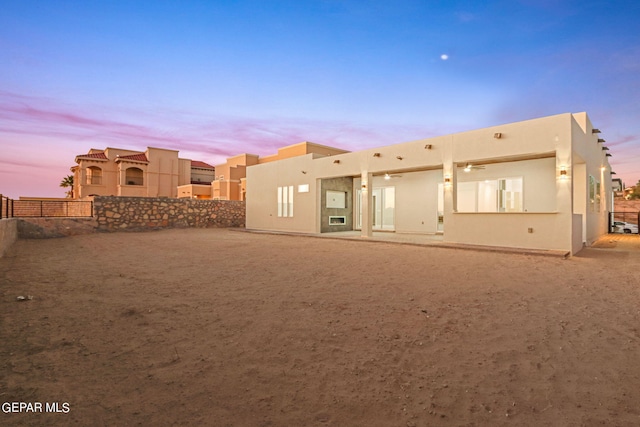rear view of house with fence and stucco siding