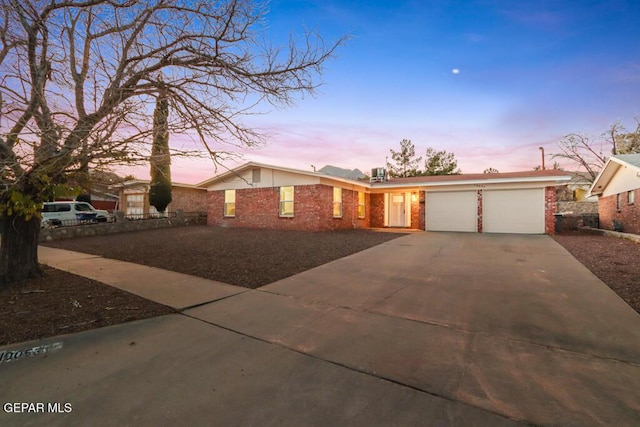 view of front of home with a garage, concrete driveway, and brick siding