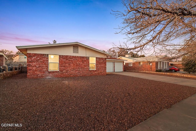 view of side of property with driveway, an attached garage, and brick siding