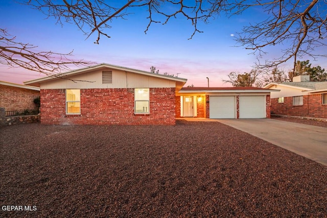 single story home with concrete driveway, brick siding, and an attached garage