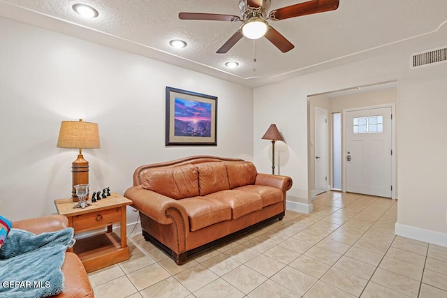 living area featuring visible vents, a textured ceiling, baseboards, and light tile patterned flooring