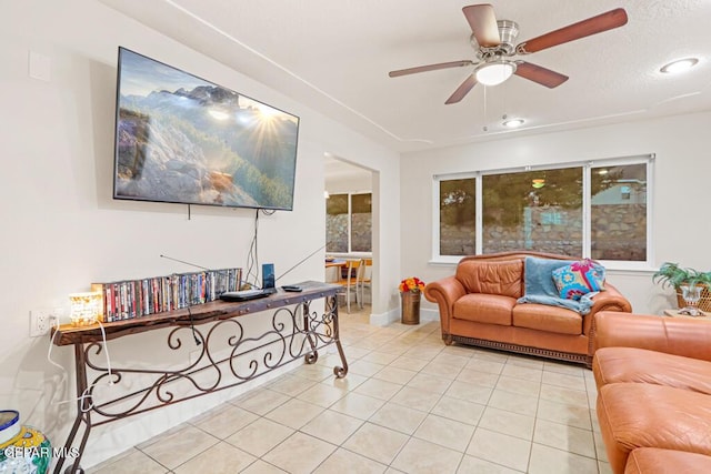 living area featuring light tile patterned floors, ceiling fan, and a textured ceiling