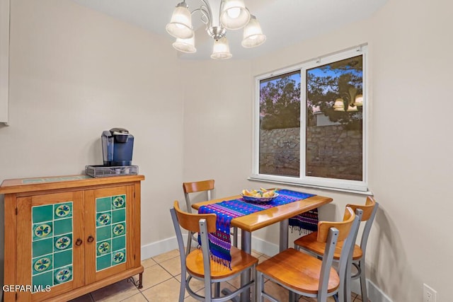 dining space with a chandelier, light tile patterned flooring, and baseboards