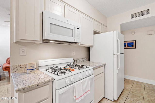 kitchen featuring white appliances, baseboards, visible vents, a textured ceiling, and light tile patterned flooring