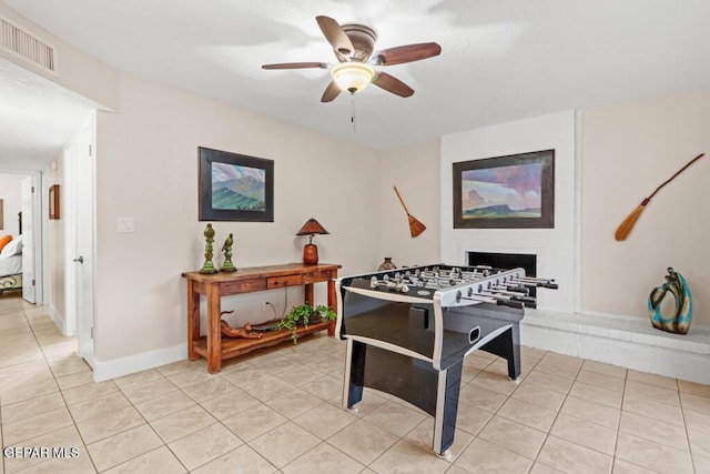 rec room featuring light tile patterned floors, baseboards, visible vents, a ceiling fan, and a brick fireplace