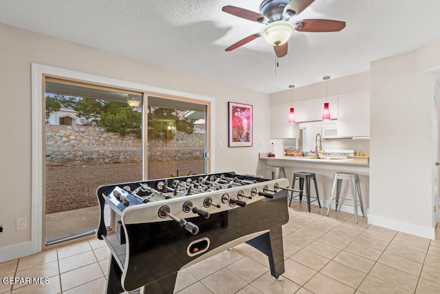 playroom featuring light tile patterned floors, ceiling fan, a sink, and baseboards