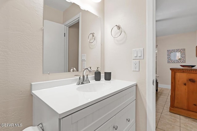 bathroom with a textured wall, tile patterned flooring, and vanity