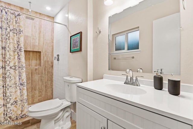 full bathroom featuring wood finished floors, tiled shower, vanity, and toilet