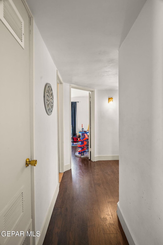 hall featuring wood finished floors, visible vents, and baseboards