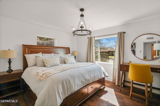 bedroom featuring dark wood finished floors, visible vents, and a notable chandelier