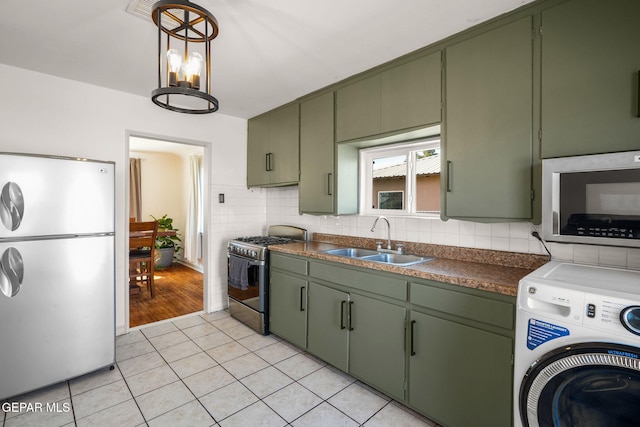 kitchen with green cabinets, appliances with stainless steel finishes, washer / clothes dryer, and a sink