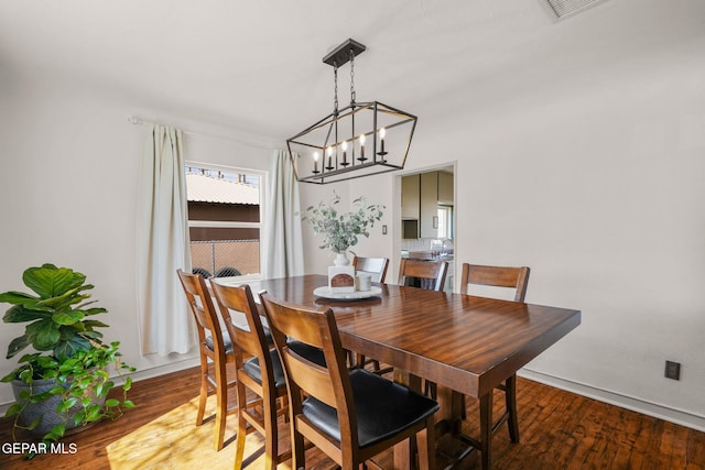 dining room featuring a chandelier, wood finished floors, visible vents, and baseboards