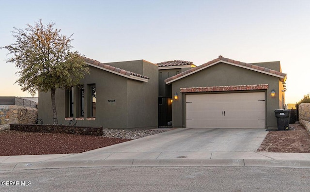 view of front facade featuring driveway, a tiled roof, an attached garage, and stucco siding