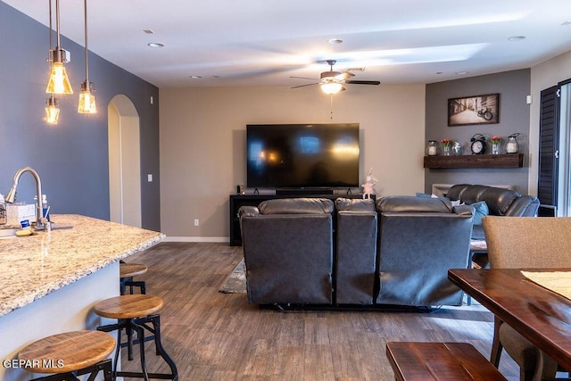 living area featuring arched walkways, ceiling fan, recessed lighting, baseboards, and dark wood finished floors