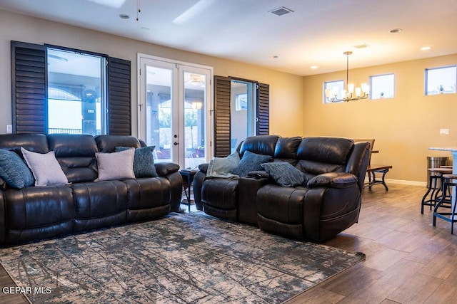 living room with a chandelier, visible vents, baseboards, and wood finished floors