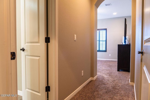 corridor featuring carpet floors, baseboards, visible vents, and arched walkways