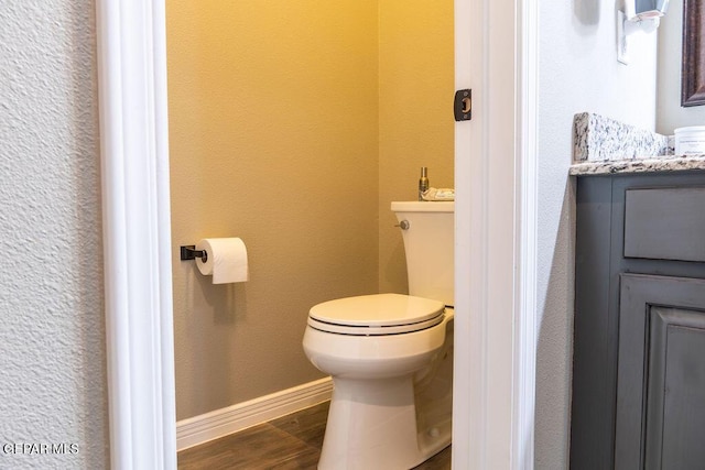 bathroom with vanity, wood finished floors, toilet, and baseboards