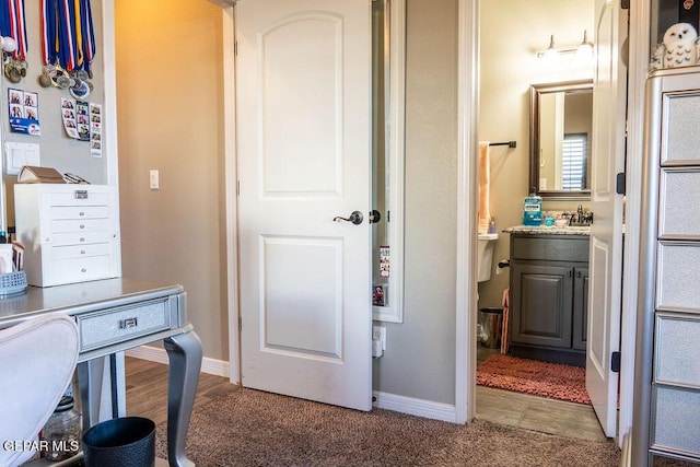 office with a sink, baseboards, and wood finished floors