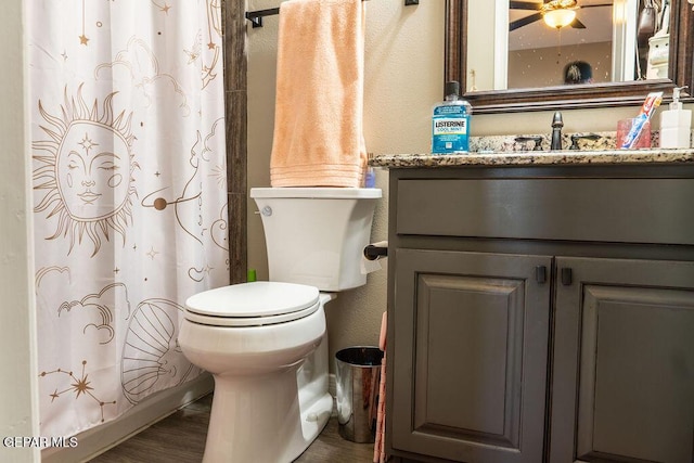 bathroom with toilet, curtained shower, wood finished floors, and vanity